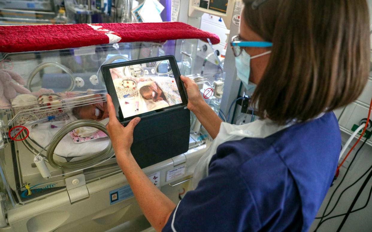 A nurse takes a video of a premature baby to send to the parents as visiting hours are restricted due to the Covid-19 virus in the maternity ward at Frimley Park Hospital in Frimley, southwest England - Steve Parsons/AFP
