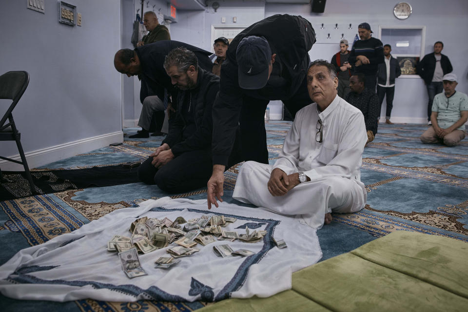 A worshiper donates money for the Palestinian people as people pray during a service at the Islamic Society of Bay Ridge mosque on Friday, Oct. 13, 2023, in the Brooklyn borough of New York. In Muslim communities across the world, worshippers gathered at mosques for their first Friday prayers since Hamas militants attacked Israel, igniting the latest Israel-Palestinian war. (AP Photo/Andres Kudacki)