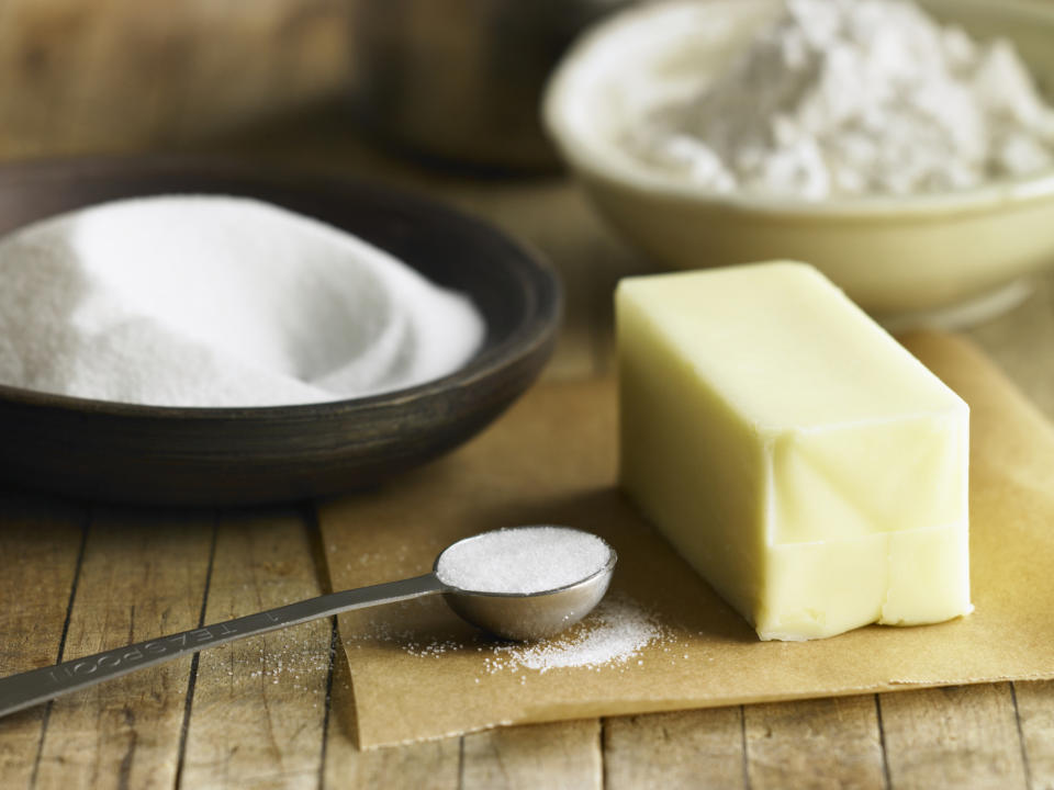 Baking ingredients on a table: flour, sugar, butter, and a measuring spoon