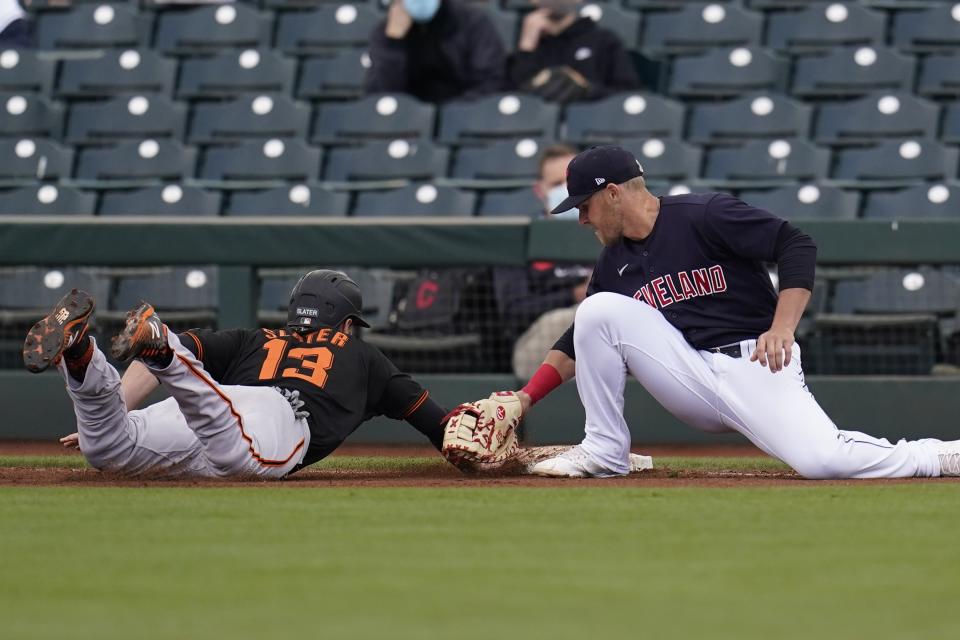 Cleveland Indians first baseman Jake Bauers, right, applies a late tag on a pickoff throw as San Francisco Giants' Austin Slater (13) dives safely back to first base during the fourth inning of a spring training baseball game Tuesday, March 23, 2021, in Goodyear, Ariz. (AP Photo/Ross D. Franklin)