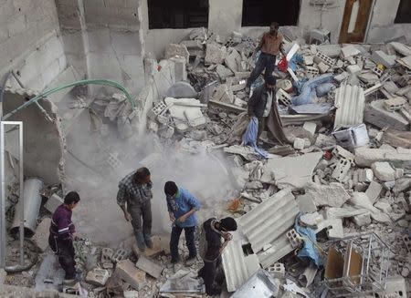 Residents search for belongings amongst rubble of damaged buildings after what activists said was an airstrike by forces loyal to Syria's President Bashar al-Assad, in the Damascus suburb of Saqba November 14, 2014. REUTERS/Msallam Abd Albaset