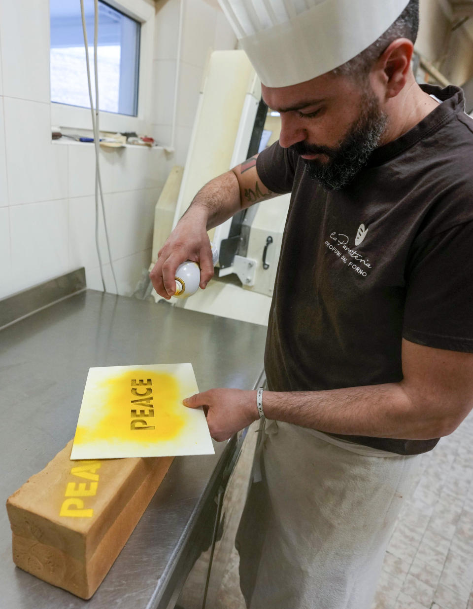 Baker Matteo Cunsolo prepares the 'bread for peace' in his laboratory in Parabiago near Milan in northern Italy, Thursday, March 17, 2022. Cunsolo used saffron and the infusion of a Thai plant to make a bicolor loaf of bread with the colors of the Ukraine national flag and butter-sprayed the word 'peace' on its sides in solidarity with the war-battered country. (AP Photo/Luca Bruno)