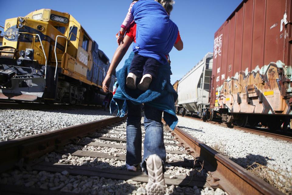 <p>Migrants walk along train tracks toward the U.S.-Mexico border fence on November 25, 2018 in Tijuana, Mexico.</p>