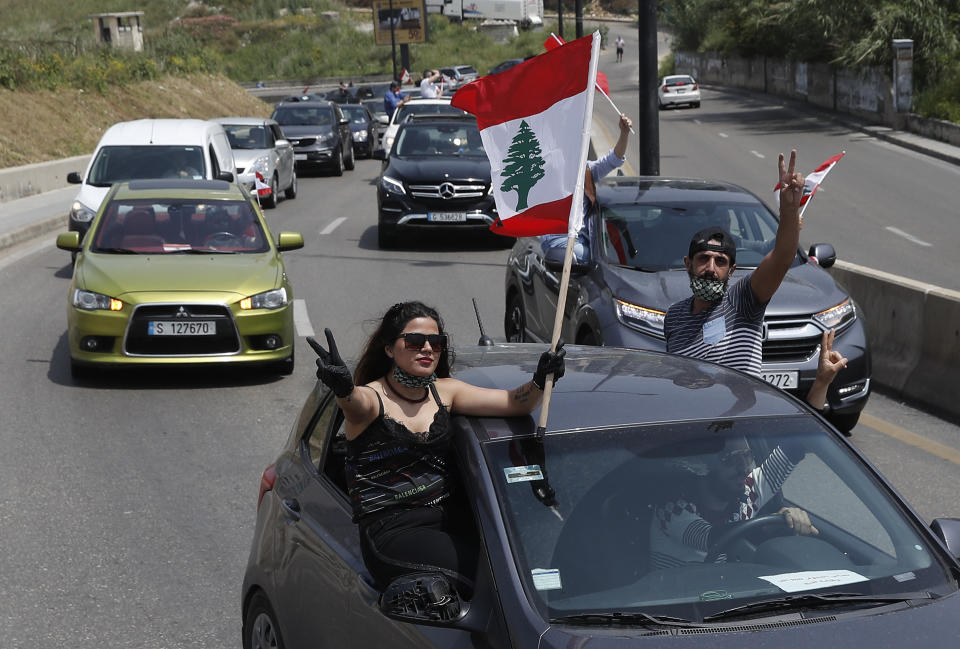 Anti-government protesters wave Lebanese flags from their cars as they protest by driving through the streets to express rejection of the political leadership they blame for the economic and financial crisis, in Beirut, Lebanon, Tuesday, April 21, 2020. Lebanon's parliament began Tuesday a three-day legislative session at a Beirut theater so that legislators can observe coronavirus social distancing measures, as protests against the country's ruling elite in the crisis-hit country resumed. (AP Photo/Hussein Malla)