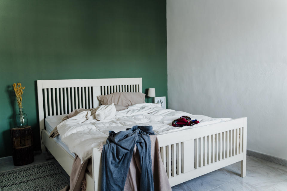 Clothes strewn over large bed.