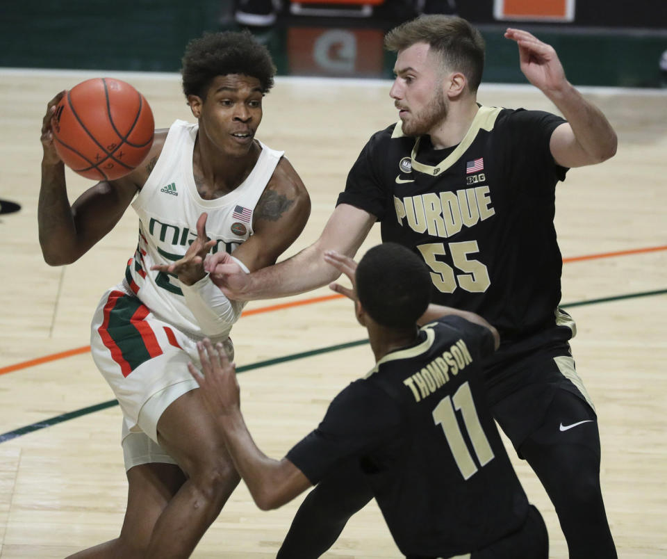 Miami guard Kameron McGusty (23) looks to pass the ball around Purdue guards Sasha Stefanovic (55) and Isaiah Thompson (11) during the first half of an NCAA college basketball game Tuesday, Dec. 8, 2020, in Coral Gables, Fla. (Al Diaz/Miami Herald via AP)