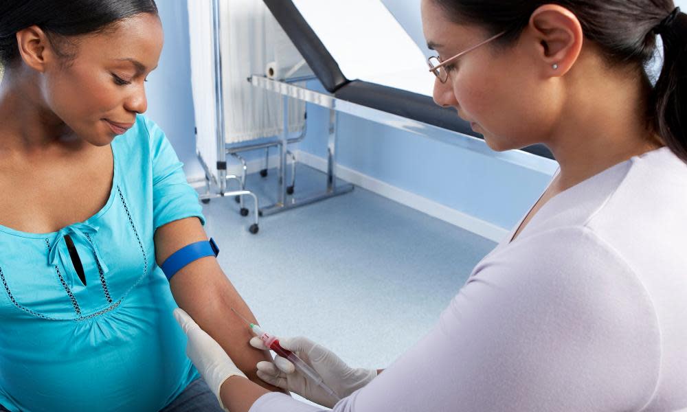 A midwife taking a blood sample from a pregnant woman