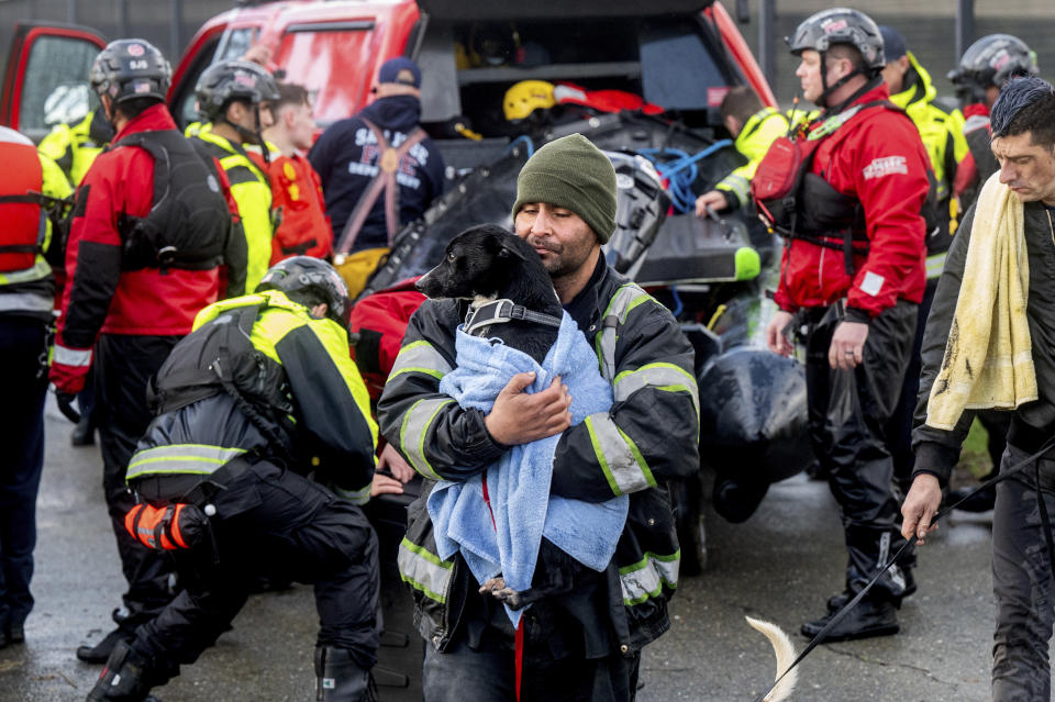 A man, who declined to give his name, carries a dog after being rescued from a homeless encampment surrounded by Guadalupe River floodwater on Sunday, Feb. 4, 2024, in San Jose, Calif. (AP Photo/Noah Berger)