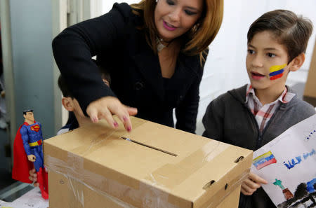 A woman accompanied by children casts her vote during an unofficial plebiscite against Venezuela's President Nicolas Maduro's government, in Lima, Peru, July 16, 2017. REUTERS/Mariana Bazo