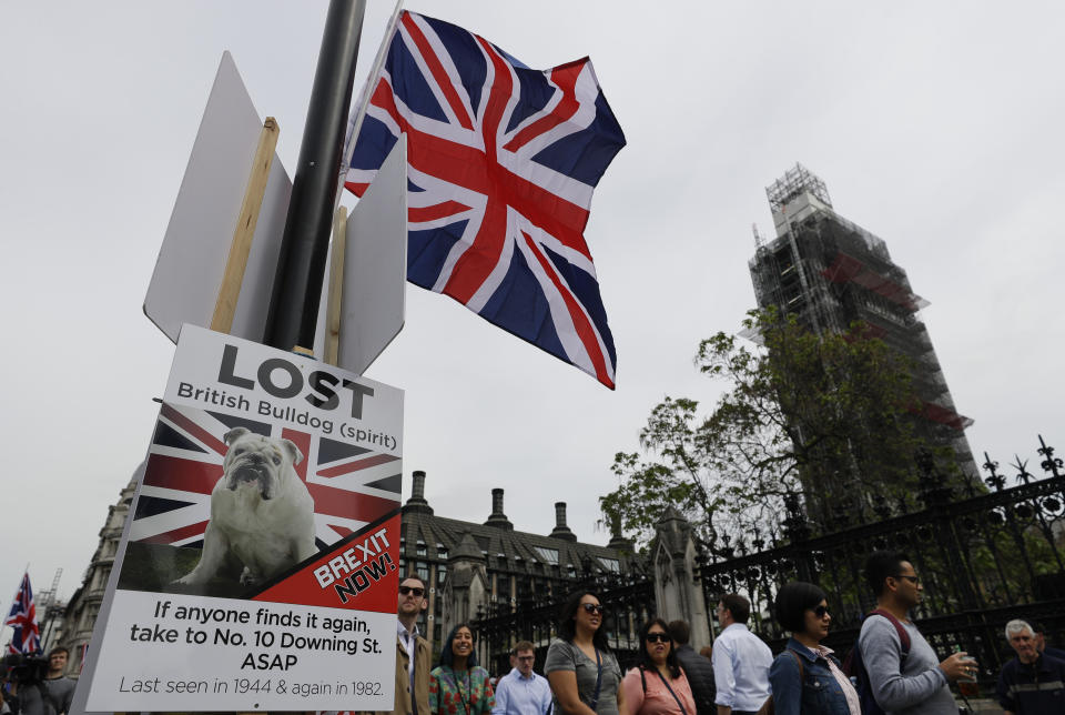 Pedestrians pass a pro-Brexit banner on a lamp post near Parliament in London, Wednesday, May 22, 2019. British Prime Minister Theresa May was under pressure Wednesday to scrap a planned vote on her tattered Brexit blueprint — and to call an end to her embattled premiership — after her attempt at compromise got the thumbs-down from both her own Conservative Party and opposition lawmakers.(AP Photo/Kirsty Wigglesworth)