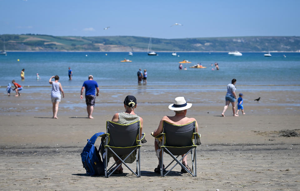 WEYMOUTH, ENGLAND - JUNE 15: A couple look out at the beach on June 15, 2022 in Weymouth, England. Hot air originating in North Africa and travelling up through Spain brings temperatures of up to 32c to the UK in the coming days. (Photo by Finnbarr Webster/Getty Images)