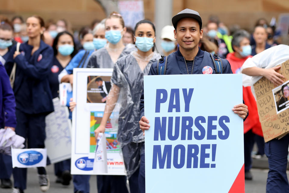 Protesters hold placards during a nurse and midwife protest in Sydney, Australia. Main placard reads 