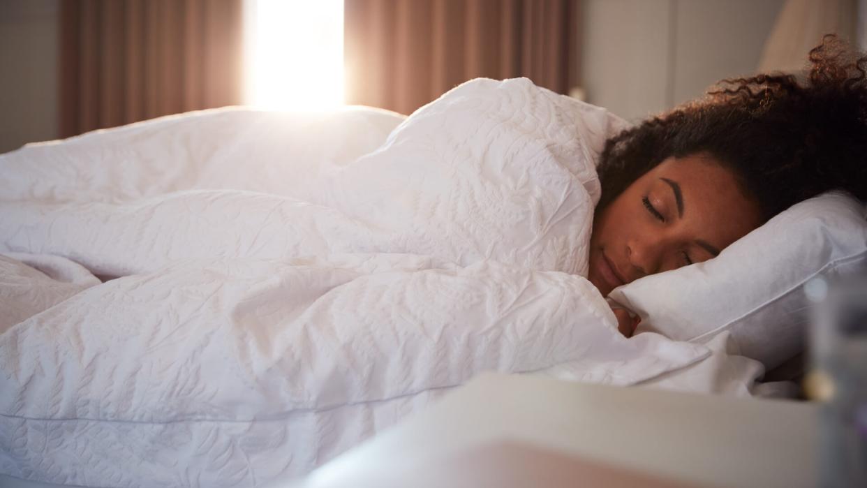 Peaceful Woman Asleep In Bed As Day Break Through Curtains.