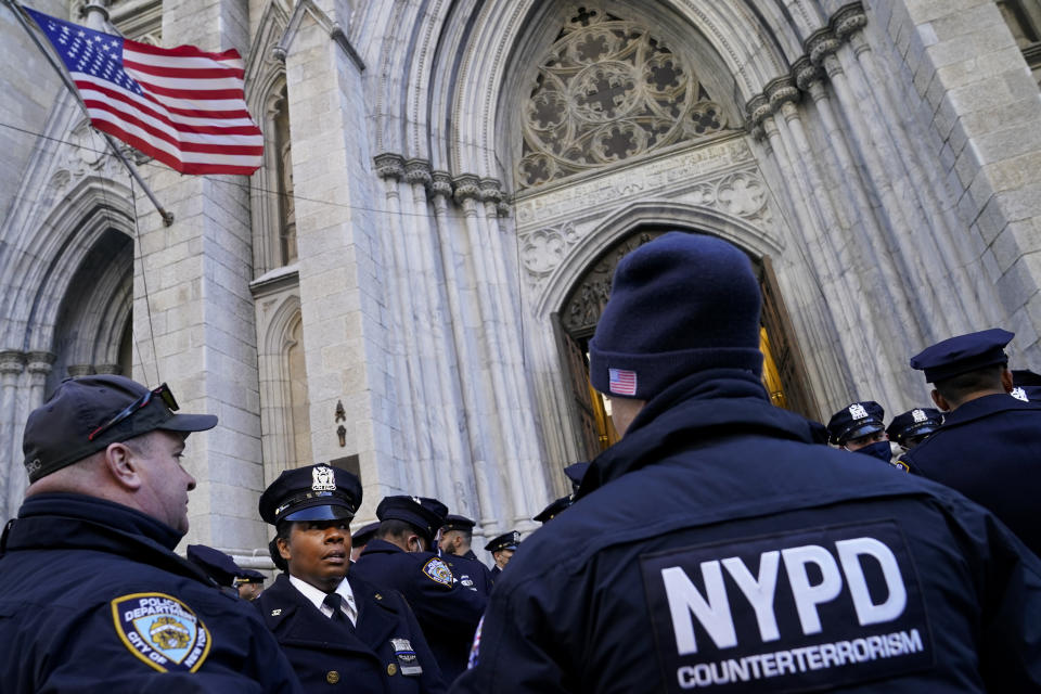 NYPD officers stand outside on Fifth Avenue before the casket of New York City Police Officer Wilbert Mora is delivered to St. Patrick's Cathedral for his wake, Tuesday, Feb. 1, 2022, in New York. Mora and Officer Jason Rivera were fatally wounded when a gunman ambushed them in an apartment as they responded to a family dispute. (AP Photo/John Minchillo)