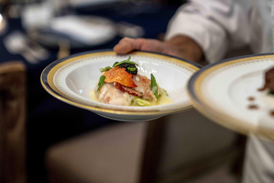 White House executive chef Cris Comerford holds dishes during a media preview for the State Dinner with President Joe Biden and French President Emmanuel Macron in the State Dining Room of the White House in Washington, Wednesday, Nov. 30, 2022. The dinner will include a butter poached Maine lobster, beef with shallot marmalade, American artisanal cheeses, and an orange chiffon cake for desert. (AP Photo/Andrew Harnik)