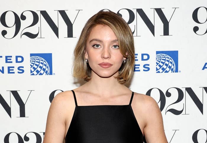 Sydney Sweeney in a posing in front of a branded backdrop