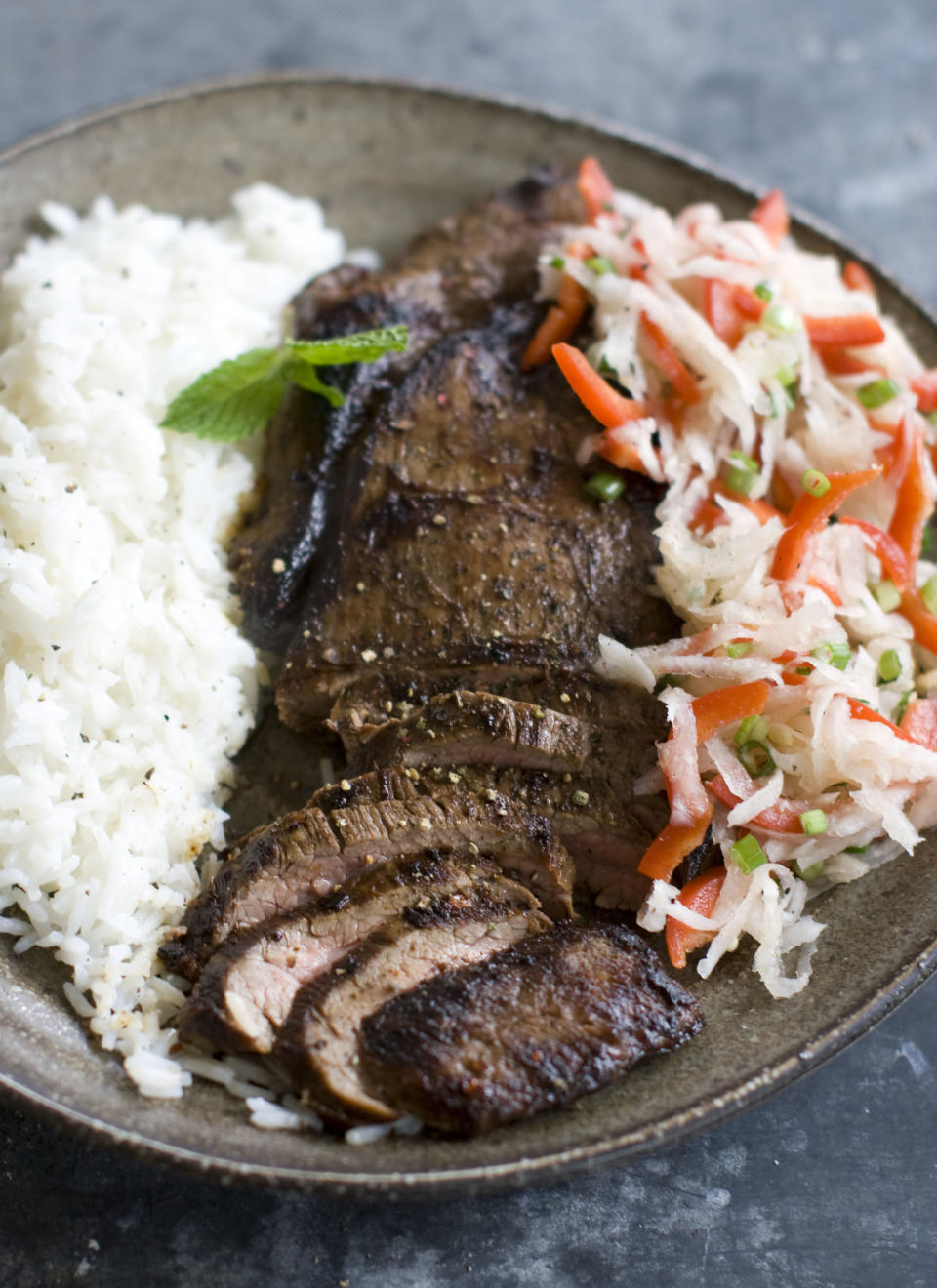 This Dec. 2, 2013 photo shows pan seared flank steak with daikon slaw in Concord, N.H. Daikon radish resemble giant white carrots, but have a mild peppery bite. (AP Photo/Matthew Mead)