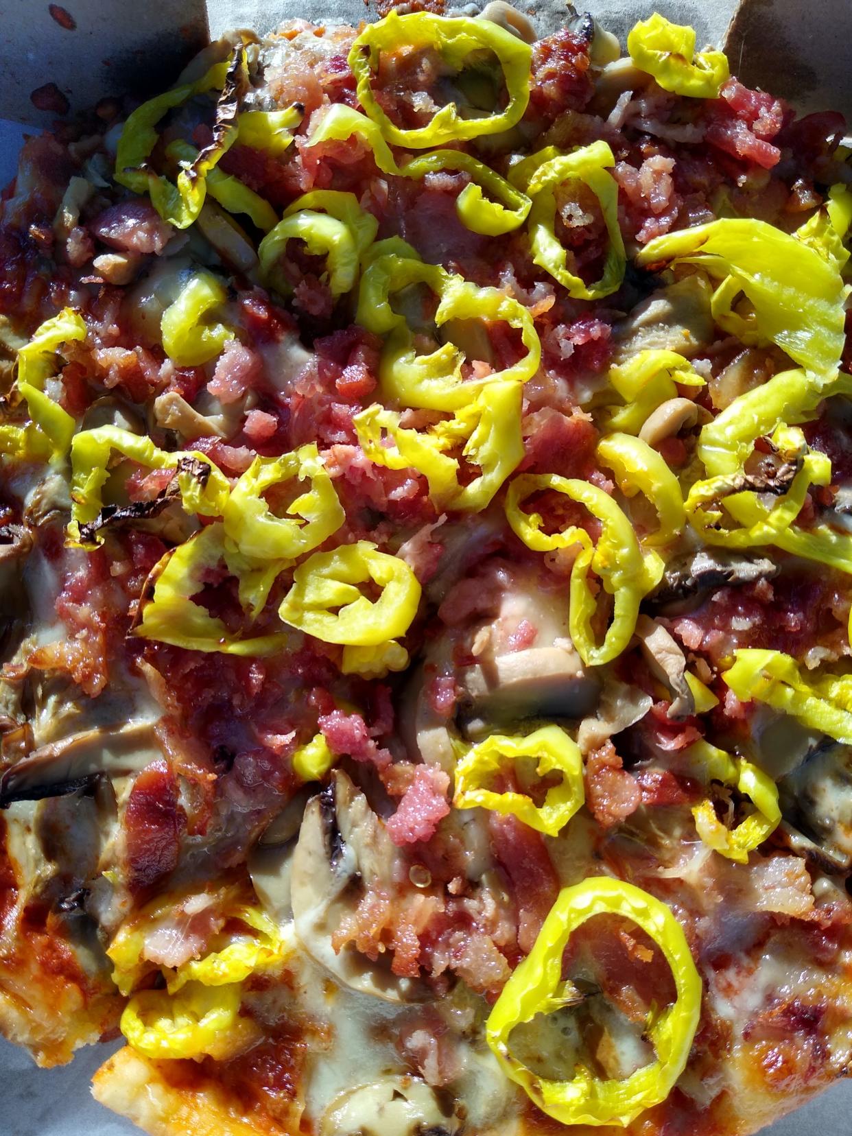 A small cheese pizza with mushrooms, bacon and banana peppers is served at Fiesta Pizza and Chicken in Goodyear Heights.