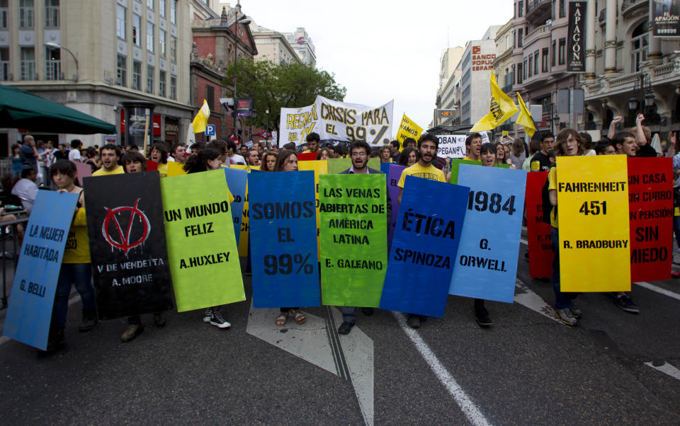 Demonstrators march towards Puerta del Sol plaza in central Madrid, Saturday May 12, 2012. Demonstrators arrived in Sol from four different directions as protesters returned to Sol to mark the anniversary of the protest movement that inspired groups in other countries. The protests began May 15 last year and drew hundreds and thousands of people calling themselves the indignant movement. The demonstrations spread across Spain and Europe as anti-austerity sentiment grew. Banners are quotes from famous books. (AP Photo/Paul White)