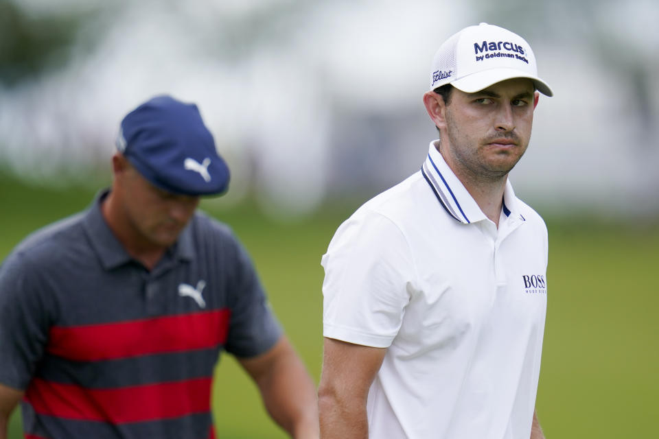 Patrick Cantlay, right, looks on as he and Bryson DeChambeau work their putts on the first hole during the final round of the BMW Championship golf tournament, Sunday, Aug. 29, 2021, at Caves Valley Golf Club in Owings Mills, Md. (AP Photo/Julio Cortez)