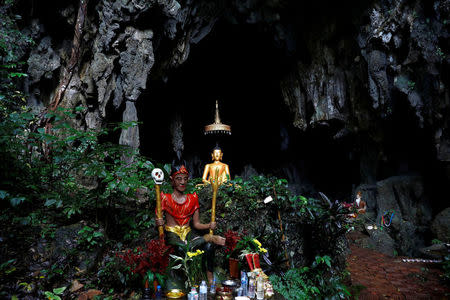 A spirit and Buddha state image are seen in front of a cave near Tham Luang cave complex, as an ongoing search for members of an under-16 soccer team and their coach continues, in the northern province of Chiang Rai, Thailand, July 2, 2018. REUTERS/Soe Zeya Tun