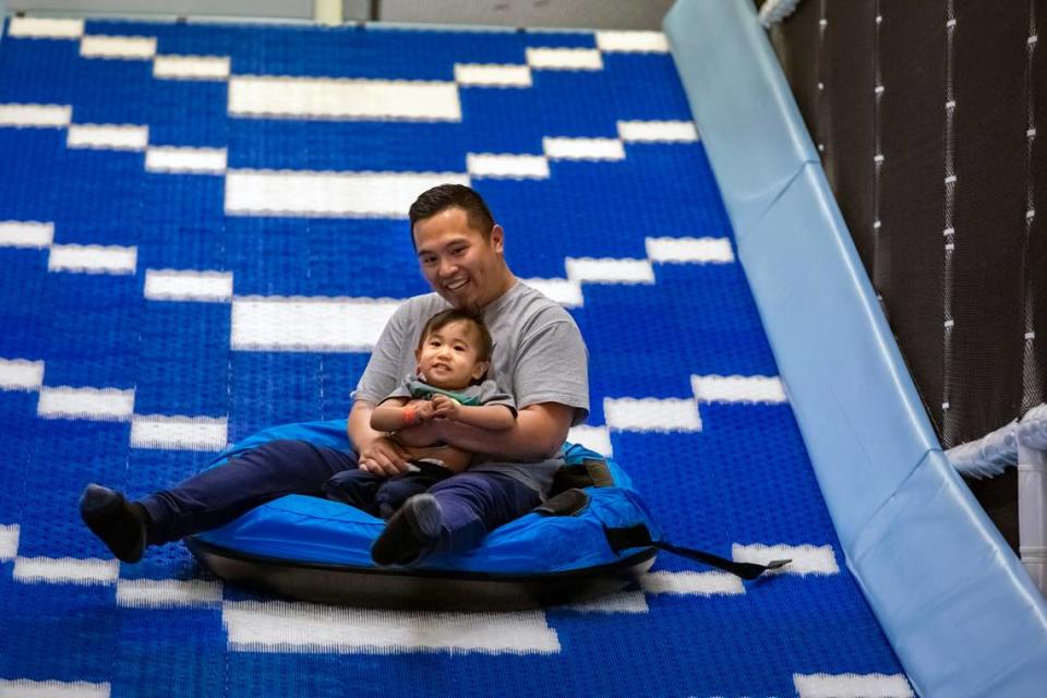 Alex Vachakone holds onto his 1-year-old son, Seth, as they go down a slide at iPlay Experience in Kennewick on Wednesday. iPlay Experience is a new indoor playground across from Costco at 8524 W. Gage Blvd. It features obstacle courses, slides, interactive floor and sand table and a virtual reality arena.