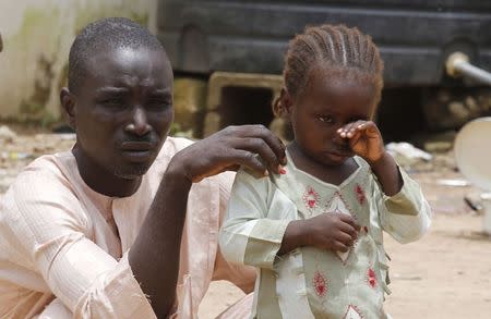 A girl rubs her eye beside her father in an internally displaced persons (IDP) camp, that was set up for Nigerians fleeing the violence committed against them by Boko Haram militants, at Wurojuli, Gombe State, September 1, 2014. REUTERS/Samuel Ini