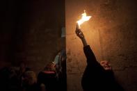 Christian pilgrim holds candles at the church of the Holy Sepulcher, traditionally believed to be the burial site of Jesus Christ, during the ceremony of the Holy Fire in Jerusalem's Old City, Saturday, April 19, 2014. The "holy fire" was passed among worshippers outside the Church and then taken to the Church of the Nativity in the West Bank town of Bethlehem, where tradition holds Jesus was born, and from there to other Christian communities in Israel and the West Bank. (AP Photo/Dan Balilty)