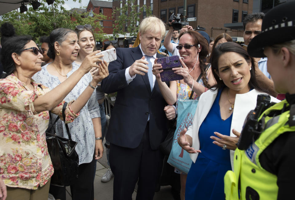 Britain's Prime Minister Boris Johnson (C) poses for selfie photographs with members of the public as he takes a walkabout with Britain's Home Secretary Priti Patel (2R) and members of West Midlands Police in Birmingham, central England on July 26, 2019. - Johnson pledged to start recruiting 20,000 new police officers as one of a number of anouncements on his government's domestic policy agenda during his debut statement in the House of Commons as Prime Minister on July 25. Meanwhile, Johnson has deliberately set Britain on a "collision course" with the EU over Brexit negotiations, Ireland's foreign minister was quoted as saying on Friday. (Photo by Geoff Pugh / POOL / AFP) (Photo credit should read GEOFF PUGH/AFP via Getty Images)