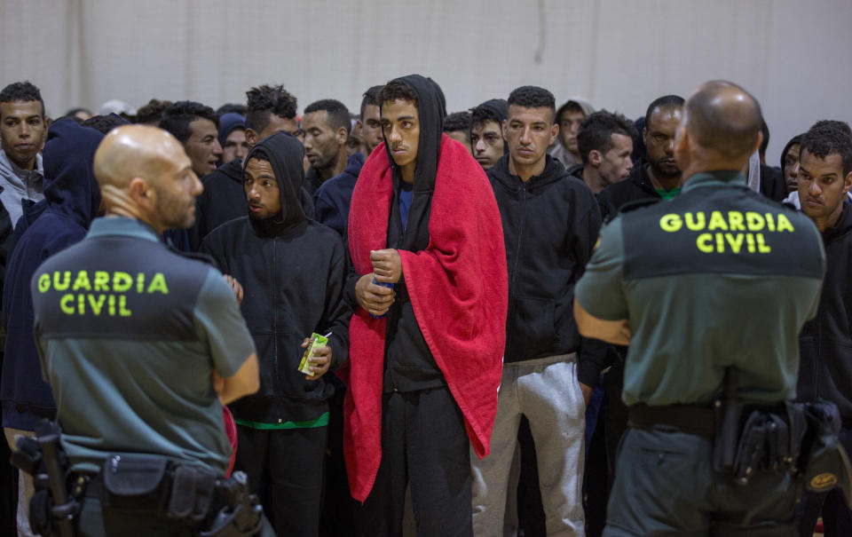 FILE - In this June 28, 2018 photo, Guardia Civil officers stand guard as migrants stay at a makeshift emergency center for migrants at Barbate's municipal sports center, in the south of Spain, after being rescued by Spain's Maritime Rescue Service in the Strait of Gibraltar. Spain appears to have stemmed a surge in illegal migration that made it the main Mediterranean entry point for migrants seeking ways into Europe by increasing Morocco's involvement in border control. (AP Photo/Emilio Morenatti, File)