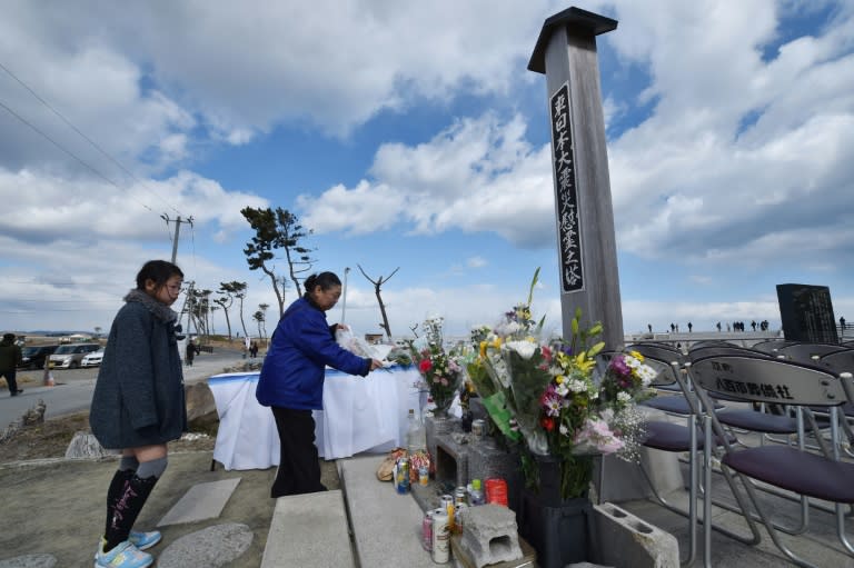 A family offers flowers for victims of the 2011 quake-tsunami disaster at a cenotaph on the sea wall near Sendai, Miyagi prefecture