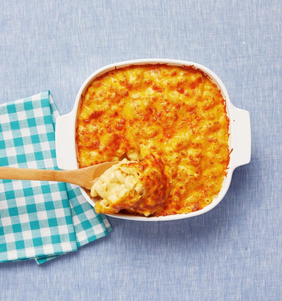 mac and cheese casserole with wooden spoon scoop and blue check napkin