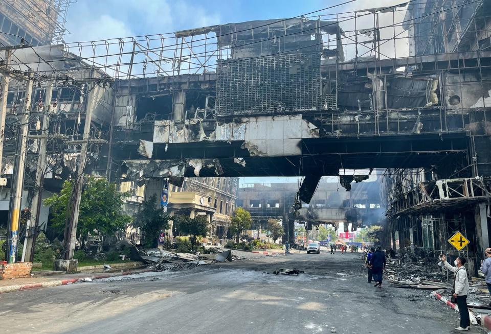 People take pictures next to a destroyed part of the Grand Diamond City hotel-casino after a fire in Poipet on December 29, 2022. - About 10 people are dead and more than a dozen on life support after a fire at a Cambodian border casino, with photos from the scene showing people desperately huddled on ledges and perched on windowsills in a bid to escape the flames.