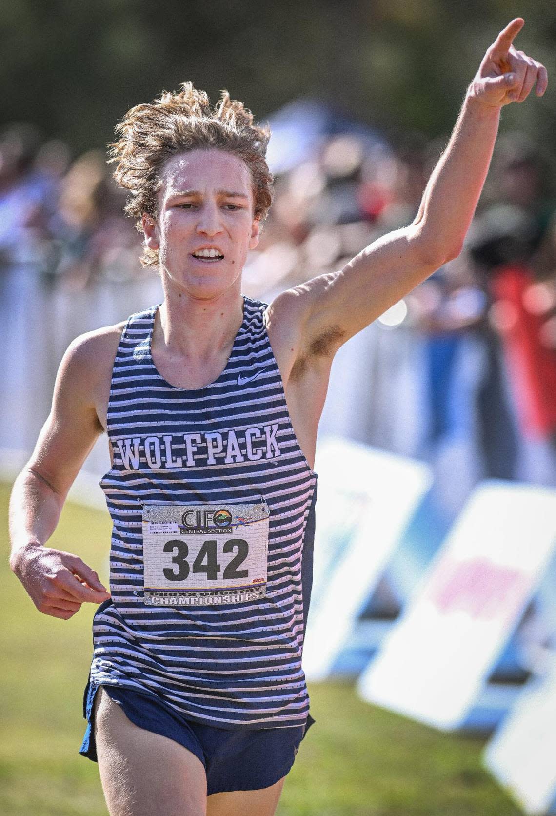 Carter Spradling gestures while crossing the line in first place in the Central Section boys Division 1 championship cross country race at Woodward Park on Thursday, Nov. 16, 2023.