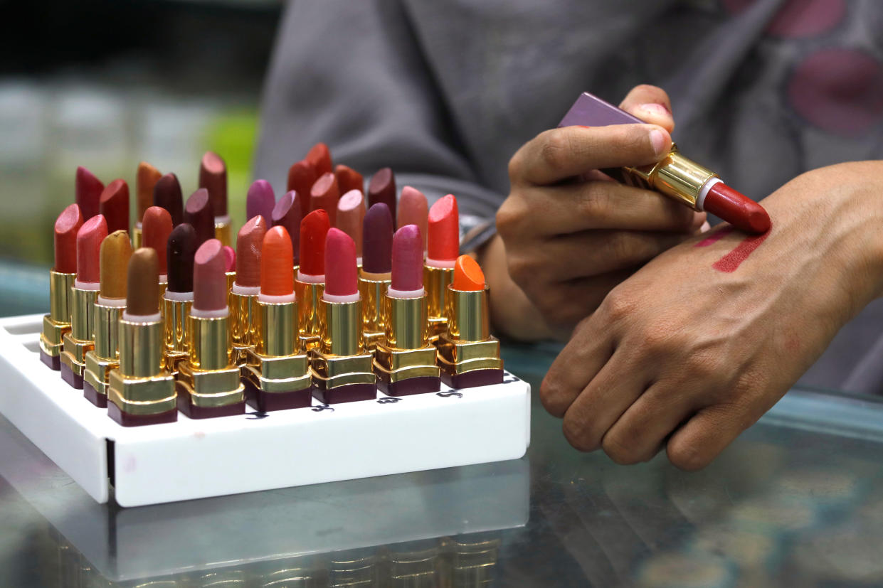 A shop attendant applies lipstick on her hand for a customer to check the shade at a store in Peshawar, Pakistan May 22, 2019. REUTERS/Fayaz Aziz