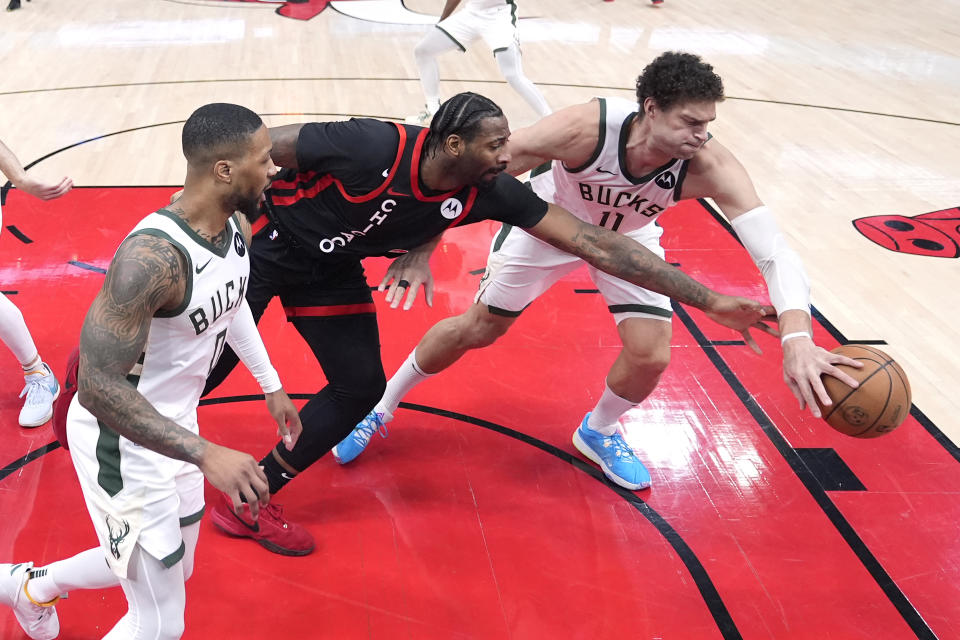 Chicago Bulls' Andre Drummond, center, and Milwaukee Bucks' Brook Lopez (11) scramble for the ball as Damian Lillard watches during the first half of an NBA basketball game Friday, March 1, 2024, in Chicago. (AP Photo/Charles Rex Arbogast)