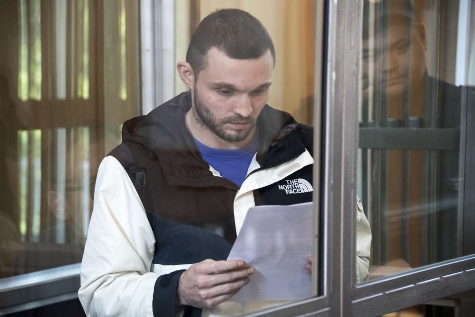 U.S. Army Staff Sgt. Gordon Black reads a paper standing in a glass cage in courtroom in Vladivostok, Russia, on Wednesday, June 19, 2024. Black is on trial on charges of theft and threatening murder in a dispute with a Russian woman. Russian state media reported that he denied the allegation of threatening murder but "partially" admitted to theft. (AP Photo)