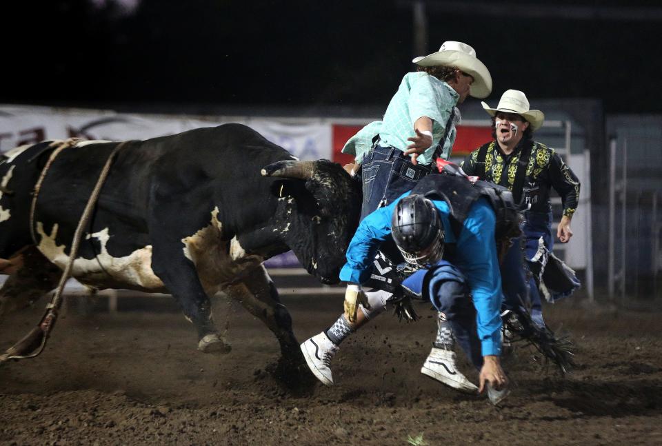 Bullfighter Blake Miller gets between the bull and bull rider Jeff Askey with bullfighter Clint Lott, back, during the Bull Riding event at the 76th annual Wild Bill Hickok PRCA Rodeo Bulls, Broncs and Barrels night Wednesday, Aug. 3, 2022, at Eisenhower Park in Abilene.