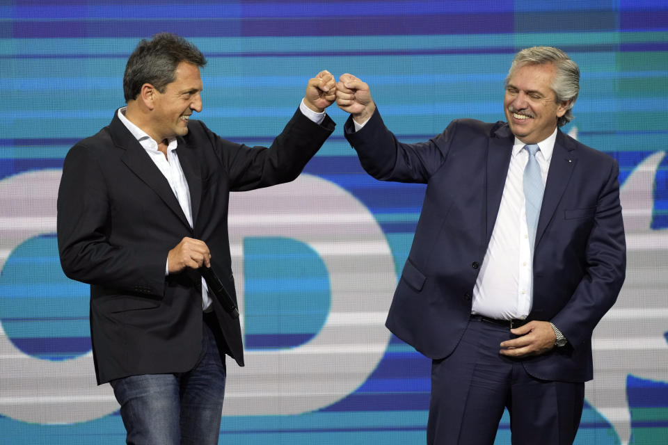 Argentine President Alberto Fernández, right, fist bumps lawmaker Sergio Massa on stage before supporters of the ruling party Front for Everyone at their campaign headquarters after polls closed for midterm legislative elections in Buenos Aires, Argentina, Sunday, Nov. 14, 2021.(AP Photo/Natacha Pisarenko)