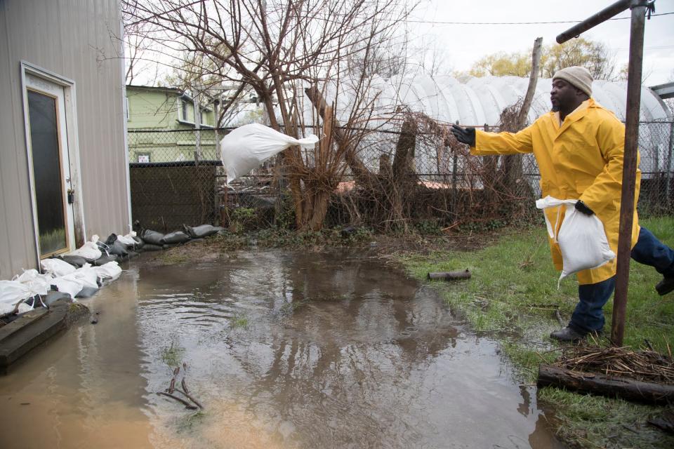 Dwight Miles, an employee from the City of Detroit General Services Department, tosses sandbags in front of a flooded house in the Jefferson Chalmers neighborhood in Detroit, Wednesday, May 1, 2019.