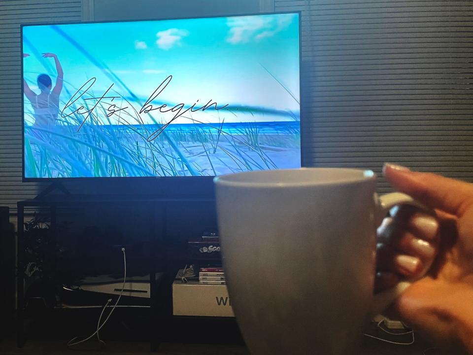 Pilates video on TV and coffee cup.