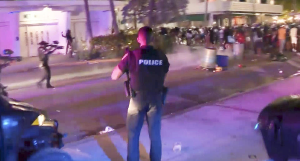 In this image taken from video, SWAT officers in bullet-proof vests disperse pepper spray balls in Miami.