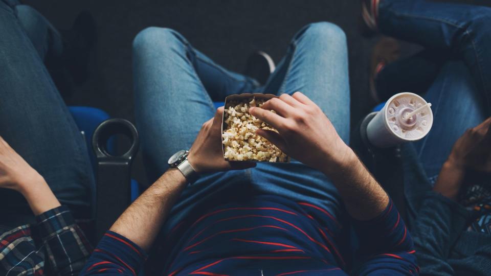 unrecognizable young man watching the movie and eating popcorn in the cinema