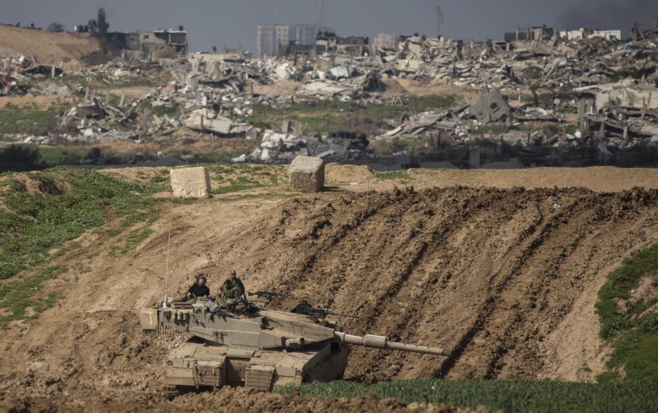 Israeli soldiers sit on a tank near the border with Gaza