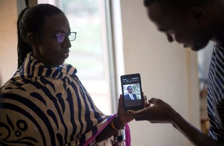 Mukarusagara Emerithe, a genocide survivor and one of the caretaker at the Agahozo-Shalom Youth Village (ASYV) built to rehabilitate children who lost their families in the 1994 Rwandan genocide, uses a mobile phone to show a photograph of her husband killed during the genocide in Rwamagana, Eastern Province of Rwanda April 1, 2019. Picture taken April 1, 2019. REUTERS/Jean Bizimana