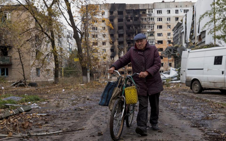 A local resident walks in front of damaged residential buildings in the town of Avdiivka