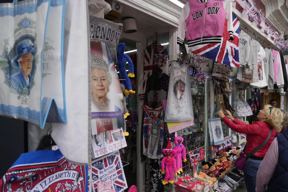 FILE - People stop by a shop displaying various souvenirs of the late Queen Elizabeth II in Windsor, England, Thursday, Sept. 15, 2022. Hotels, restaurants and shops are packed as royal fans pour into the heart of London to experience the flag-lined roads, pomp-filled processions and brave a mileslong line for the once-in-a-lifetime chance to bid adieu to Queen Elizabeth II. (AP Photo/Gregorio Borgia, File)
