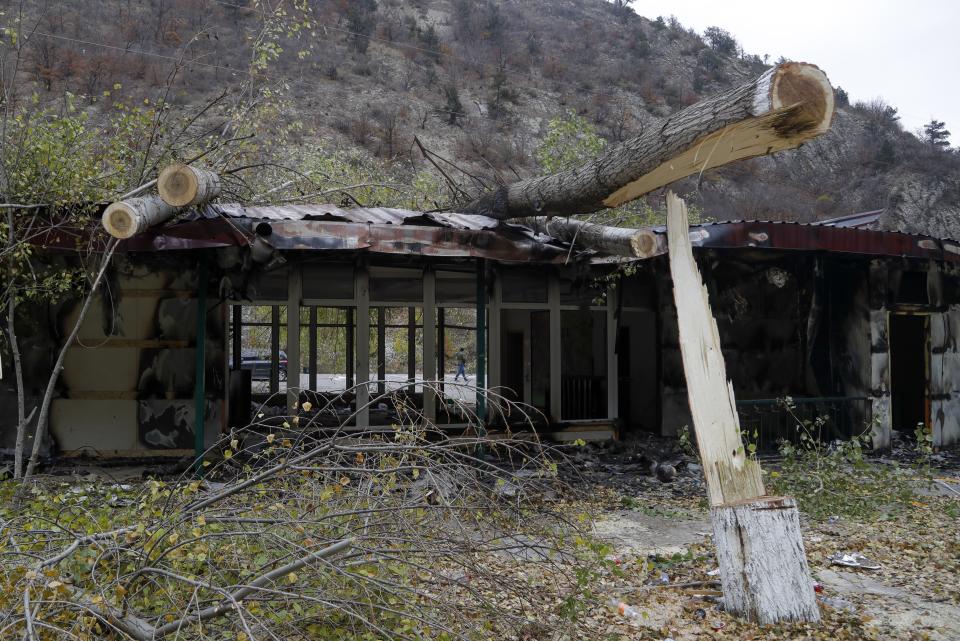 A man walks past a damaged gasoline station in Kalbajar in separatist region of Nagorno-Karabakh, Monday, Nov. 16, 2020. It is unclear when any civilians might try to settle in Karvachar, which will now be known by its Azeri name Kalbajar, or elsewhere. Azerbaijan on Sunday postponed taking control of a territory ceded by Armenian forces in a cease-fire agreement, but denounced civilians leaving the area for burning houses and committing what it called "ecological terror." (AP Photo/Sergei Grits)