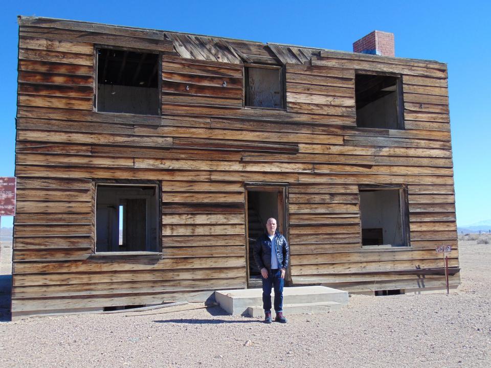 "Downwind" co-director Mark Shapiro outside the shell remains of the Apple 2 House at the Nevada National Security Site on March 7, 2023. The model home was part of a series of nuclear weapons tests in 1955. Populated with clothed mannequins during detonations, this wood-frame structure was studied as a typical American home – and how it would respond to a blast.