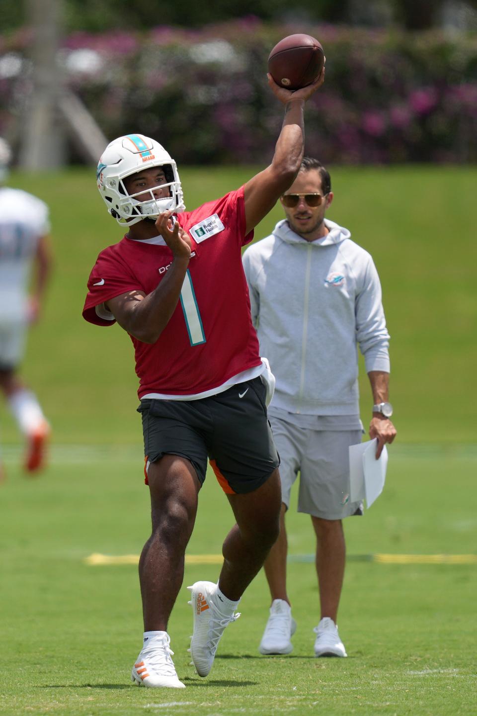 May 17, 2022; Miami Gardens, FL, USA; Miami Dolphins quarterback Tua Tagovailoa (1) passes the ball in front of head coach Mike McDaniel during OTA practice at Baptist Health Training Complex. Mandatory Credit: Jasen Vinlove-USA TODAY Sports